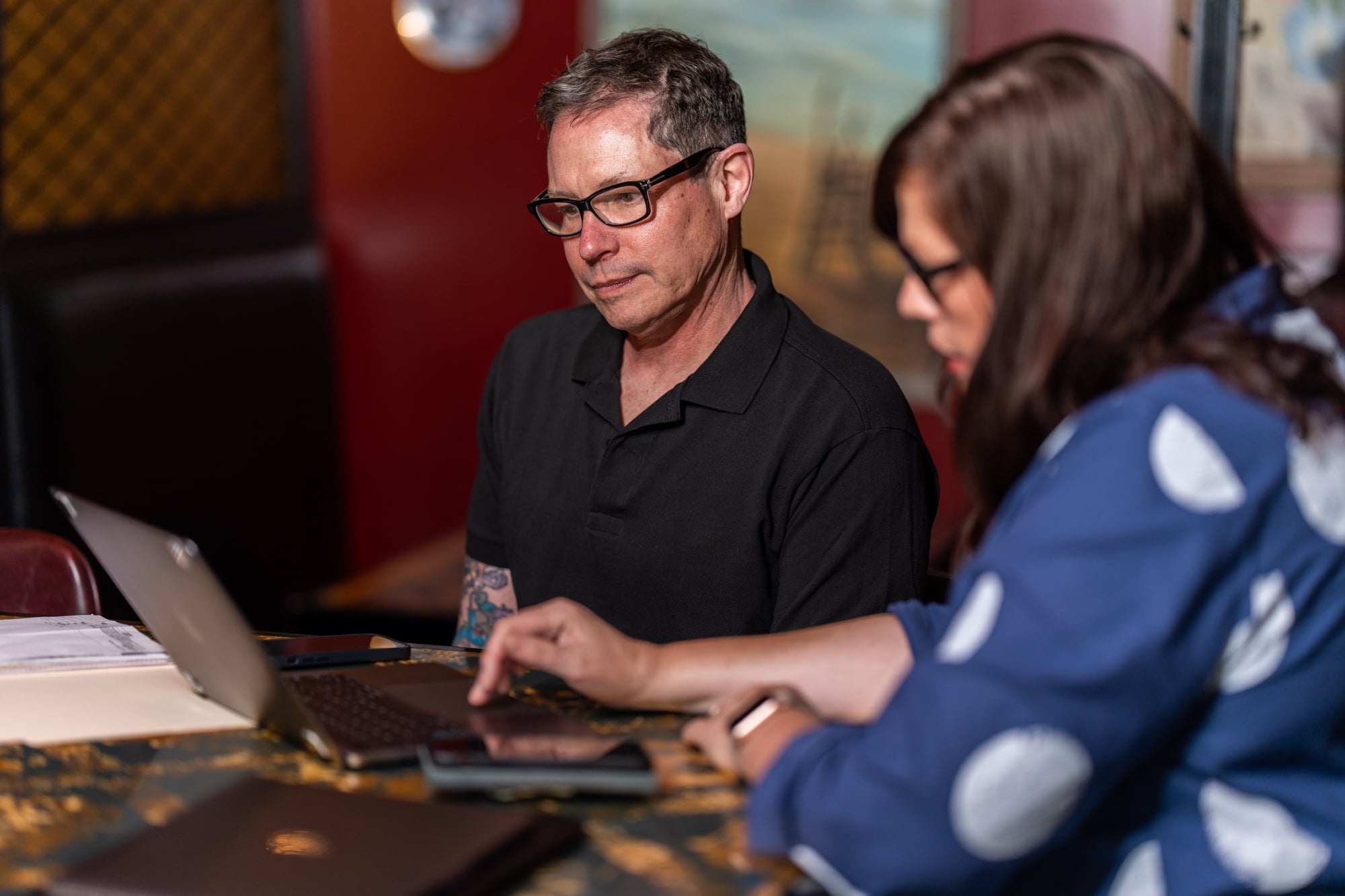 Restaurant operator and accountant sit together with a laptop